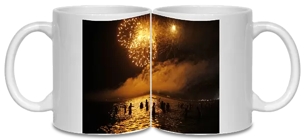 People watch fireworks as they take a bath in the Mediterranean Sea on San Juan s