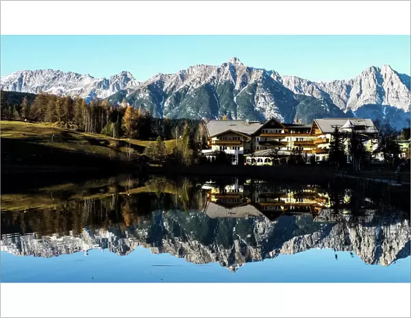Mountains are reflected in a small lake on a sunny autumn day in the western Austrian