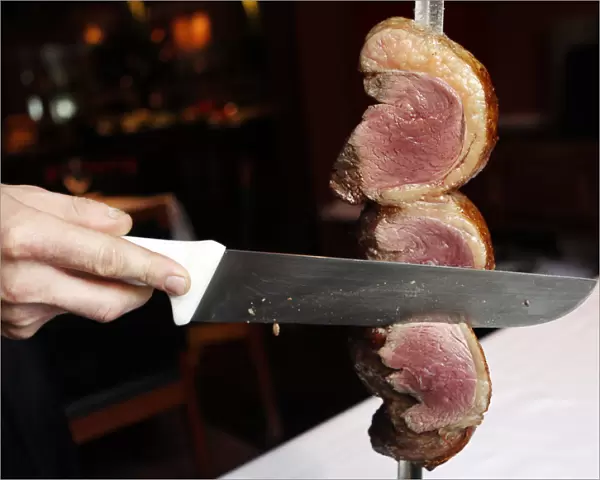 A waiter cuts a slice of Picanha meat at the Fogo de Chao Brazilian steakhouse in