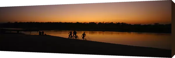 Children ride bicycles during the sunset at the bank of East Rapti River at Sauraha