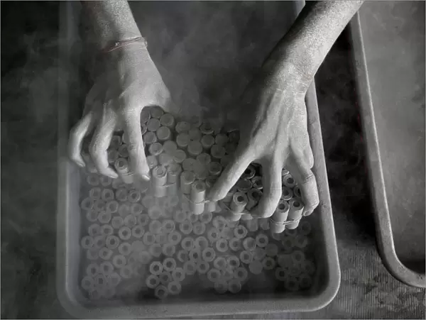 A worker removes paper rolls after filling them with gunpowder mixture to make