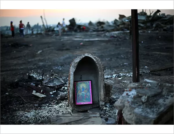 A religious image is seen in front of debris of an immigrants shacks camp after an