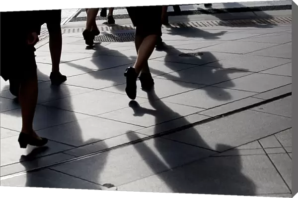 Female office workers wearing high heels and clothes of the same colour walk at a