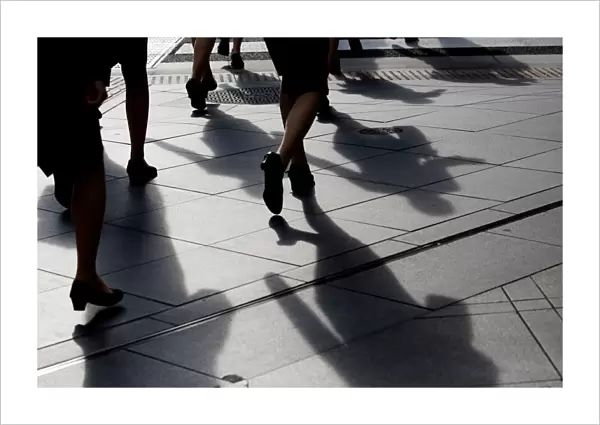 Female office workers wearing high heels and clothes of the same colour walk at a