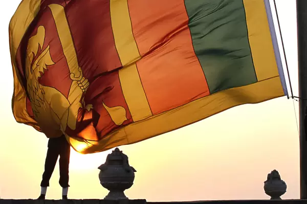 An air force officer holds the Sri Lanka national flag as the sun sets at galle face