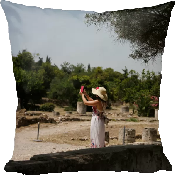 A tourist takes pictures with her phone as she visits the Roman Agora archaeological site