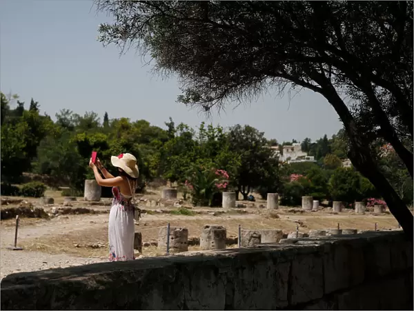 A tourist takes pictures with her phone as she visits the Roman Agora archaeological site