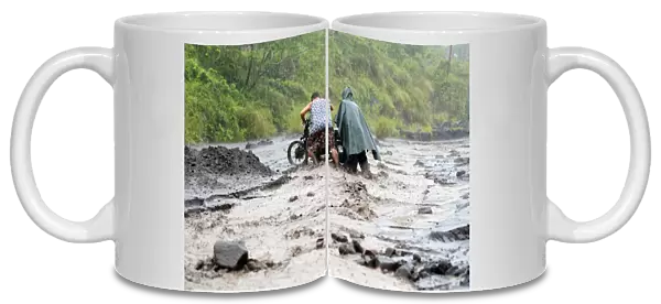 Residents push a motorcycle across a river mixed with lahar from Mount Mayon volcano in