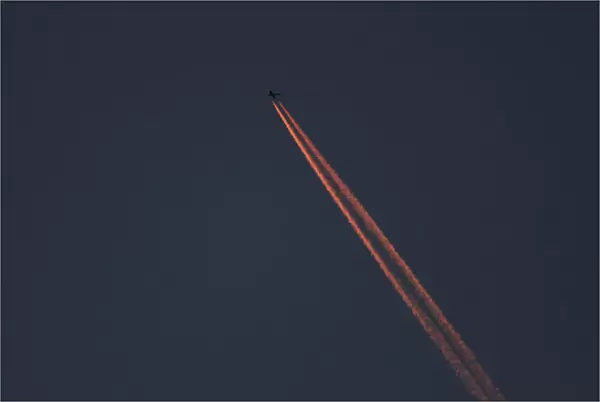 A passenger plane leaves behind contrails as it flies in the skies over London Luton
