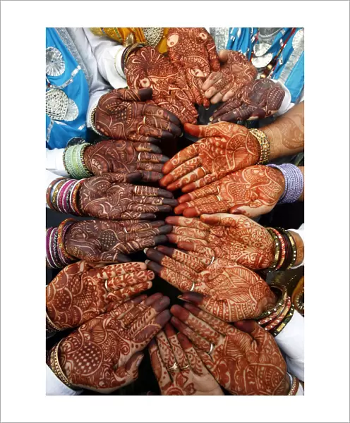 Indian women folk dancers show their hands decorated with henna paste before their