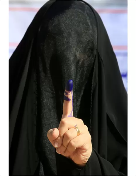 A female security member shows her ink-stained finger after casting her vote at a polling