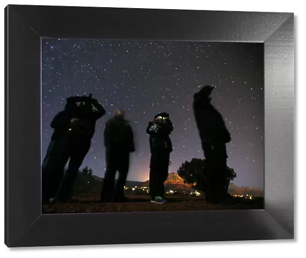 People use night vision goggles to look at the night sky during an UFO tour in the desert