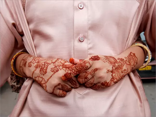 The hands of a girl, adorned with henna patterns, as she arms around her father while