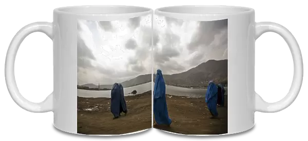 Afghan women clad in burqa walk along a road in Kabul