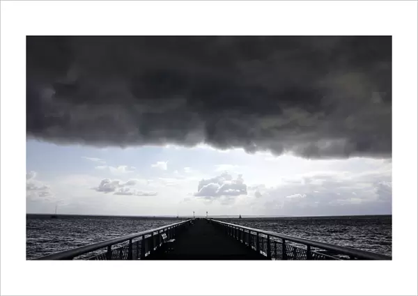 Dark clouds fill the Autumn sky over the jetty in Andernos, southwestern France