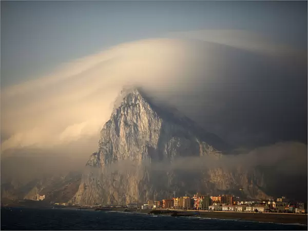 Cloud partially covers Rock of the British territory of Gibraltar at sunrise before