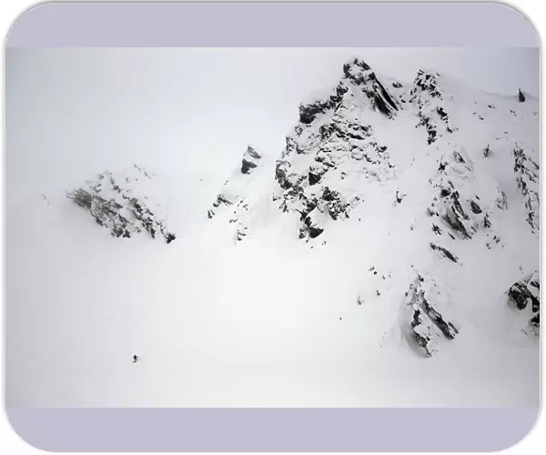 A snowboarder descends from a rough mountain slope towards Balea glaciar lake at Balea