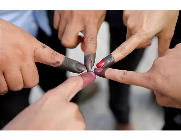 Cambodian voters take pictures of their ink stained fingers after they voted