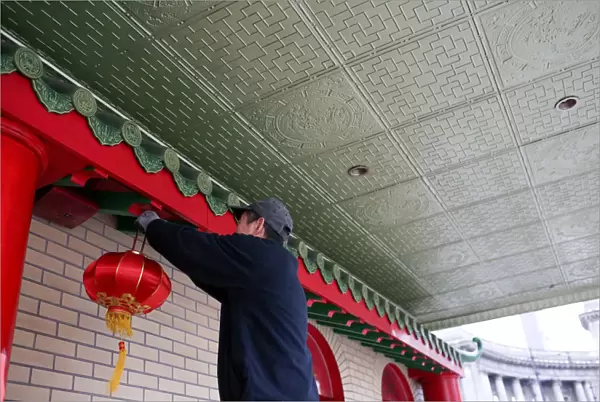 A man hangs a lantern for the Chinese Lunar New Year at Mahayana Buddhist Temple in