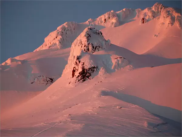At sunset, climbers and rescue personnel descend Mount Hood