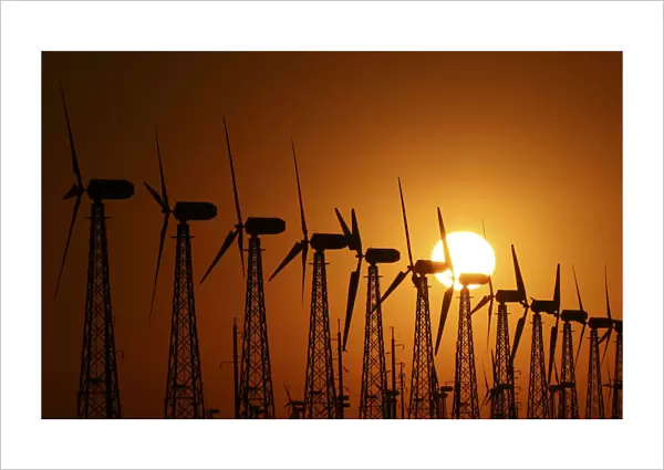 The sun sets behind power-generating turbines of a local wind farm in Crimea