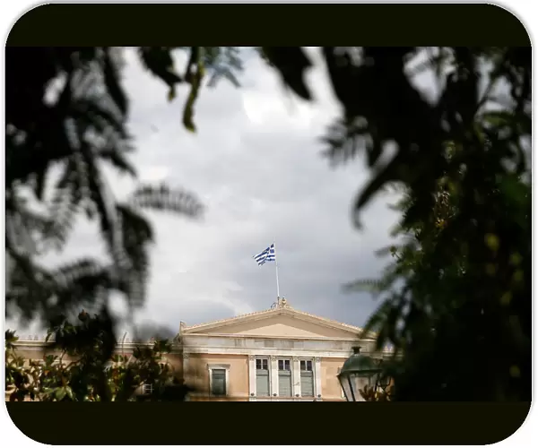 A Greek flag flutters atop the parliament building in Athens