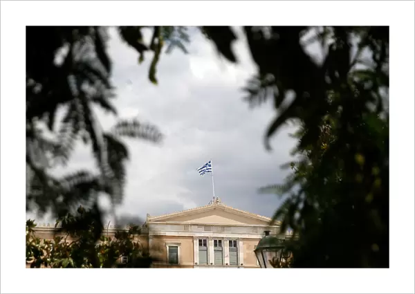 A Greek flag flutters atop the parliament building in Athens