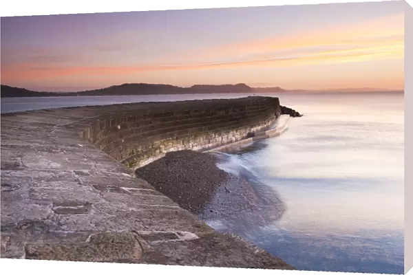 View of harbour wall at low tide during sunrise, looking across bay to Charmouth, Stonebarrow, Golden Cap and beyond