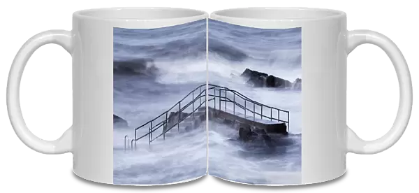 Steps of tidal swimming pool above breaking waves during incoming tide on windy morning, Bude Sea Pool, Summerleaze