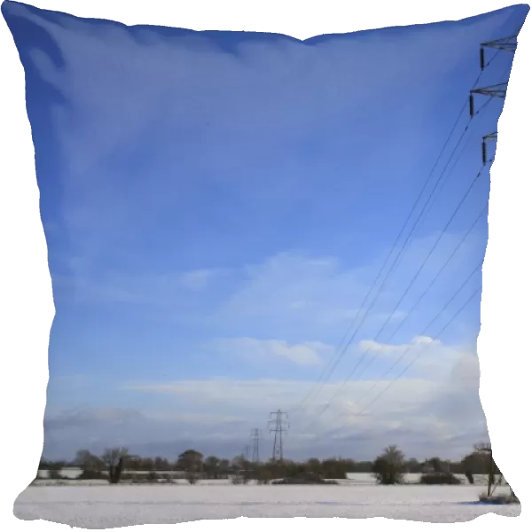 Electricity transmission pylons and overhead wires, crossing over snow covered arable farmland, Bacton, Suffolk, England, november