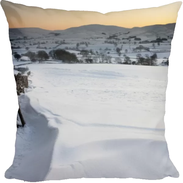 View of snow covered farmland in evening, overlooking Ravenstonedale area on northern fringe of Howgill Fells, Cumbria