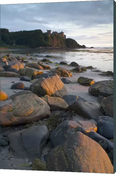 View of rocks on beach and clifftop castle at sunset, Culzean Castle, South Ayrshire, Scotland, june