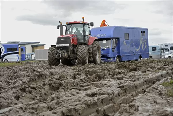 Case tractor pulling horse lorry out of muddy carpark at agricultural show, which was cancelled due to bad weather