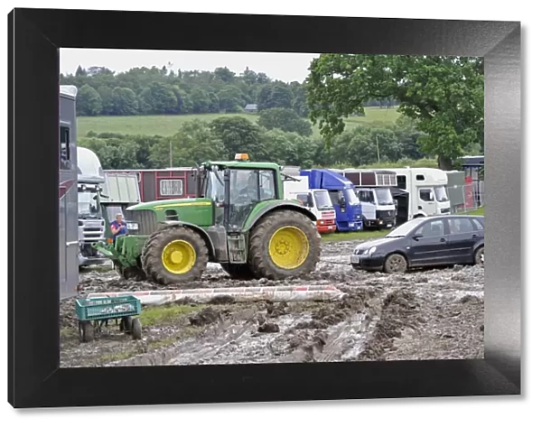 John Deere 6930 tractor pulling car out of muddy carpark at agricultural show, which was cancelled due to bad weather