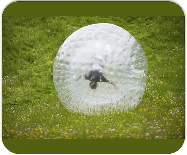 Zorbing, person rolling downhill in transparent plastic orb, Sweden, June