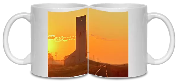 Canada, Manitoba, Culross. Grain elevator and railroad tracks at sunrise. Credit as