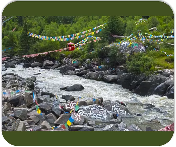 Buddhist words painted on rocks and praying flags by the river, Tagong, western Sichuan