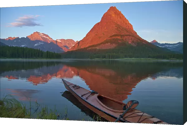 Wooden kayak in Swiftcurrent Lake at sunrise in the Many Glacier Valley of Glacier National Park