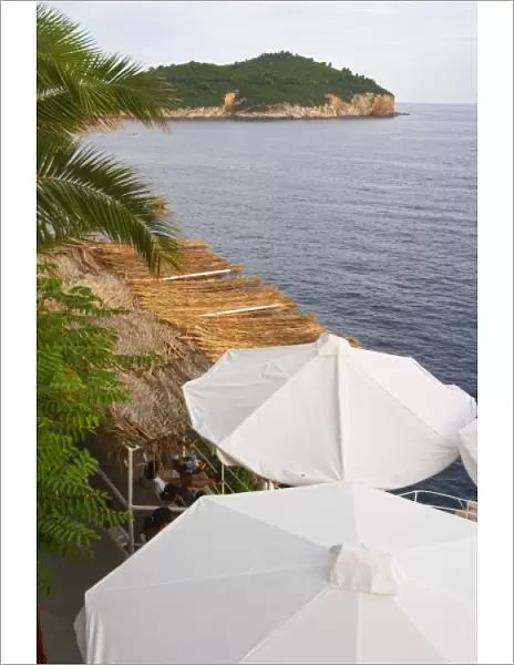 White sun shade umbrellas at a cafe on the city wall overlooking the sea and the