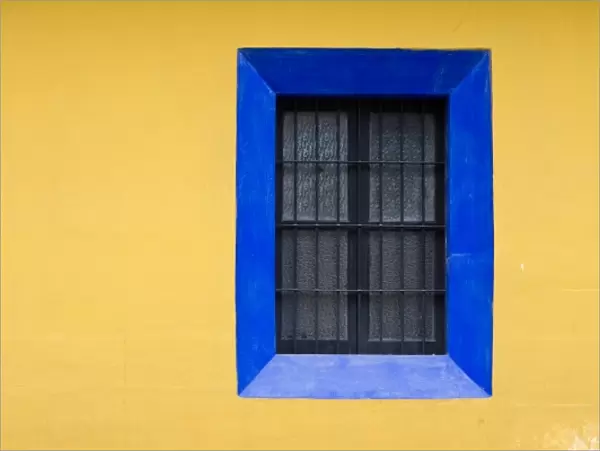 Guatemala, Antigua. Blue window against bright yellow wall