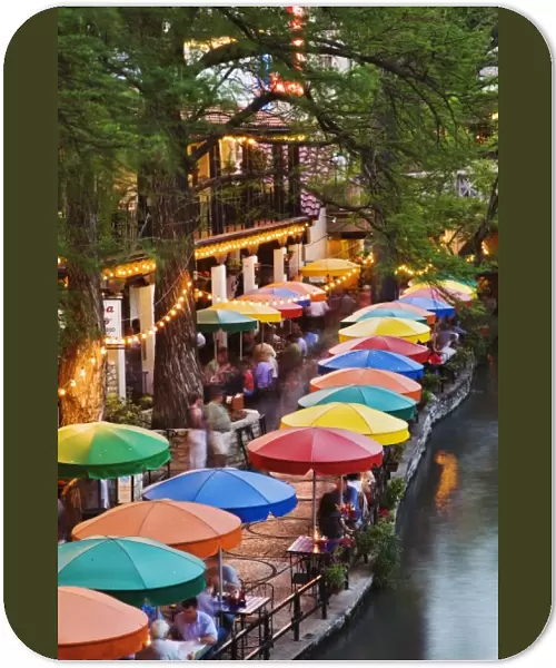 Colorful umbrellas of outdoor cafe along famous River Walk, and San Antonio River