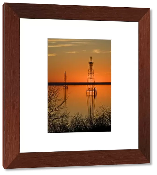 Oil well derricks in Lake Arrowhead near Wichita Falls, Texas, USA at sunset, winter