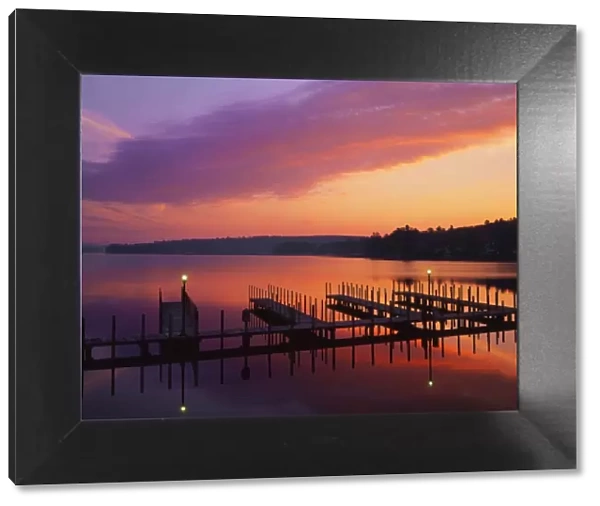 USA, New Hampshire. Colors of sunrise reflecting on dock and Lake Winnipesaukee