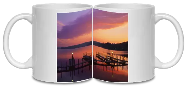 USA, New Hampshire. Colors of sunrise reflecting on dock and Lake Winnipesaukee