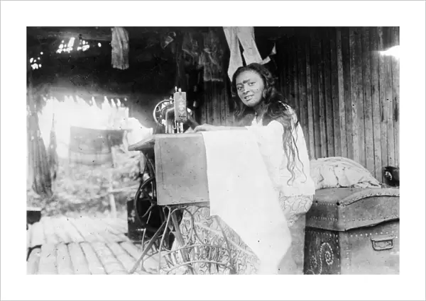 SOUTH AMERICAN INDIAN. A South American Indian woman using a sewing machine in her hut