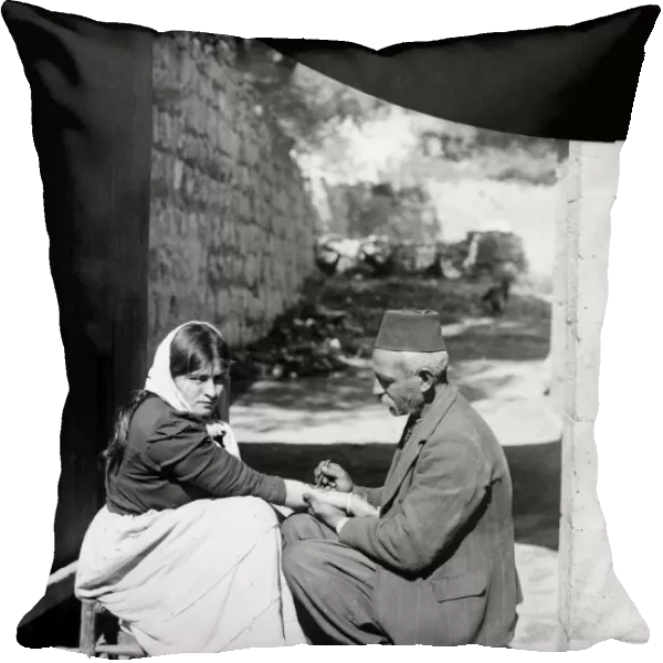 STREET TATTOO. A peasant woman receiving a tattoo on the streets of an unknown location
