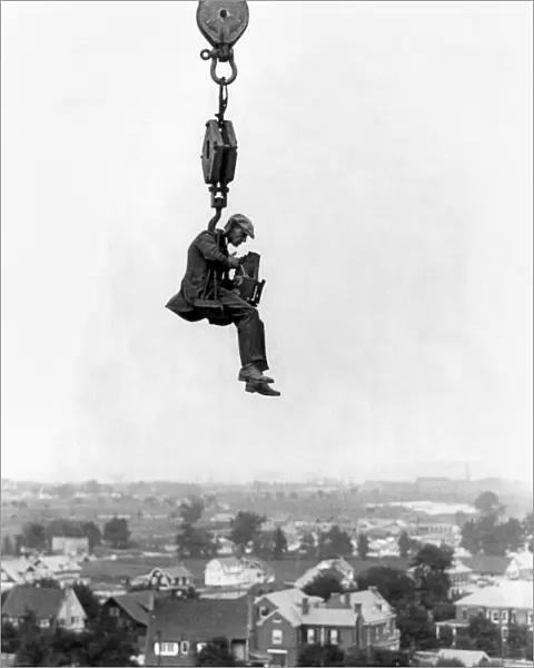 PHOTOGRAPHER, 1923. Photographer suspended from the hook of a crane over Washington D