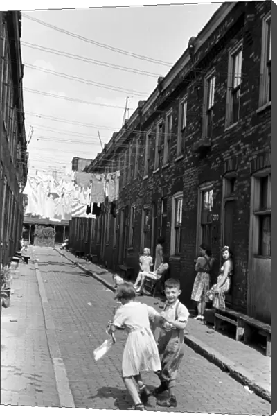 ROW HOUSES, 1938. Women and children in front of a row of low-income houses in Ambridge