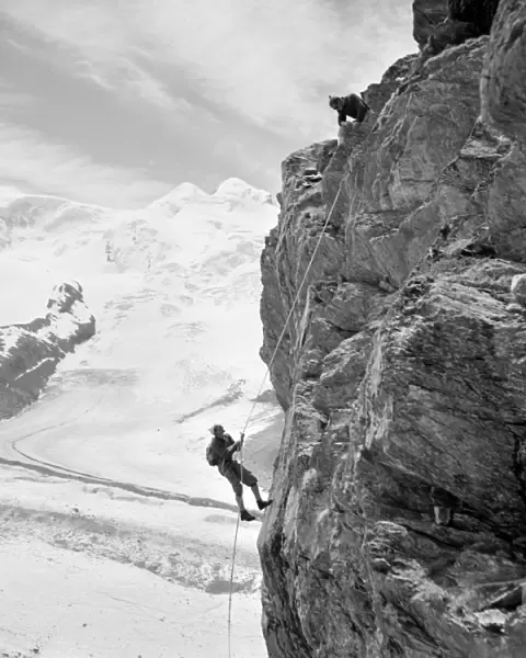 ALPINE MOUNTAINEERS, 1954. Two mountain climbers on the side of a mountain at Zermatt