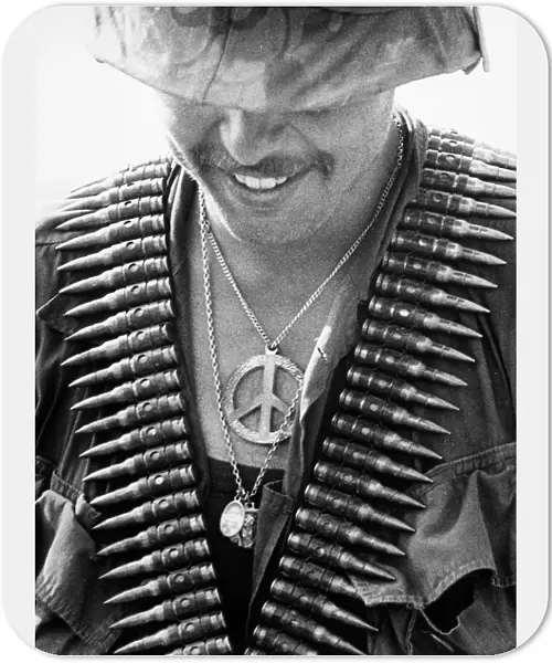 VIETNAM WAR: SOLDIER, 1970. A U. S. 61st Infantry Regiment trooper with a peace symbol and religious medals as well as a bandolier of bullets at Con Thiem, Vietnam, February 1970